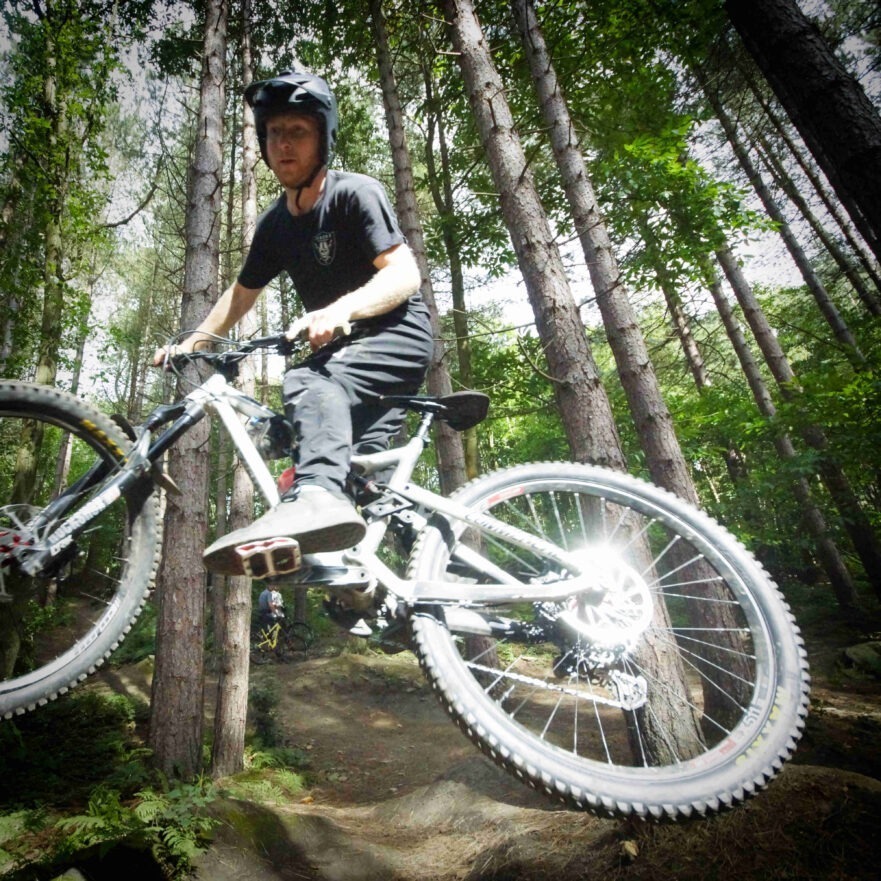 MTB rider learning mountain bike jumps, Grenoside Woods, Sheffield, Yorkshire